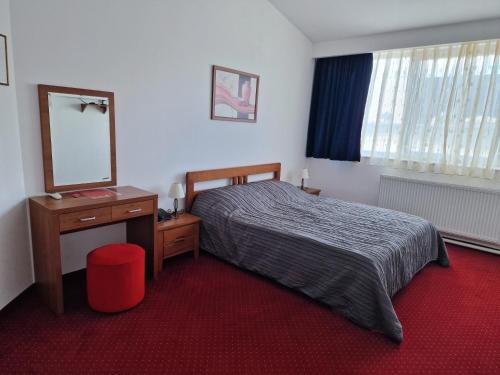 a bedroom with a bed and a dresser and a mirror at Motel Citadela 023 in Zrenjanin