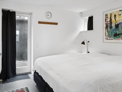 a white bedroom with a bed and a window at Holiday Home Esme - 30m from the sea by Interhome in Dannemare