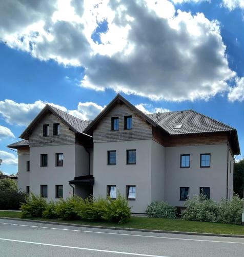a large white house with a roof at Apartmán U Merlina in Deštné v Orlických horách