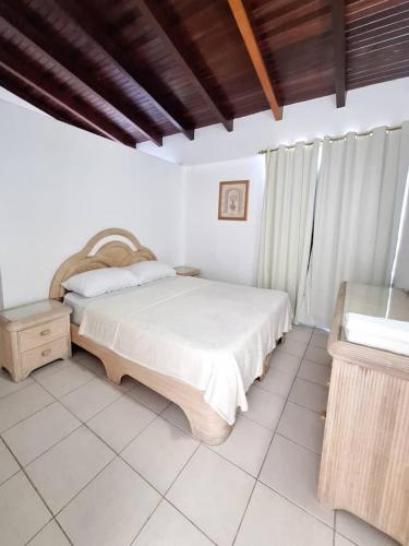 ein weißes Schlafzimmer mit einem Bett und einem Tisch in der Unterkunft Valle Alegre in El Valle del Espíritu Santo