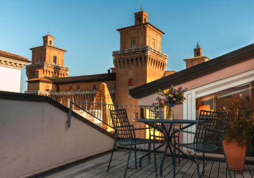 a table and chairs on a balcony with two towers at Casa D'Este - Hotel Ferrara in Ferrara