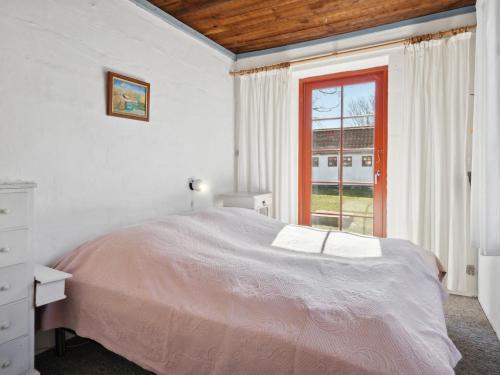 a white bedroom with a bed and a window at Holiday Home Natalija - 100m from the sea by Interhome in Læsø