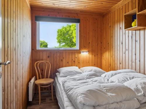 a bedroom with a bed with a window and a chair at Holiday Home Stygge - 300m from the sea by Interhome in Hadsund