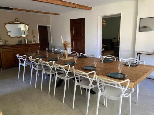 une salle à manger avec une table en bois et des chaises blanches dans l'établissement Maison de la tuilière hautes alpes piscine et boulodrome 12 personnes, à Saléon