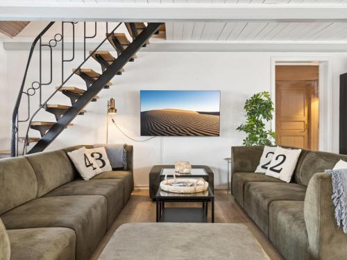 a living room with two couches and a staircase at Holiday Home Dana - 525m from the sea by Interhome in Tranekær