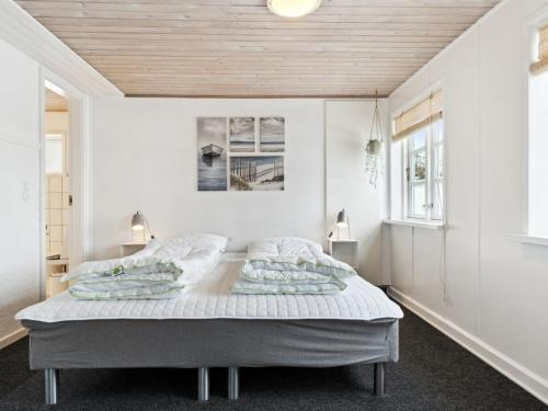 a bedroom with a large bed with white walls at Holiday Home Dana - 525m from the sea by Interhome in Tranekær