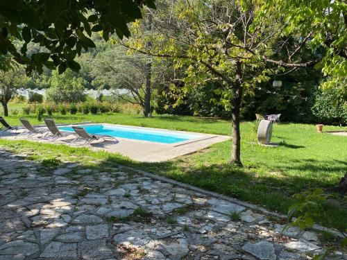 une piscine avec deux chaises et un arbre dans l'établissement Maison de la tuilière hautes alpes piscine et boulodrome 12 personnes, à Saléon