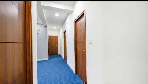 a hallway with a door and blue carpet at Hotel Maski Suties in Kondapur