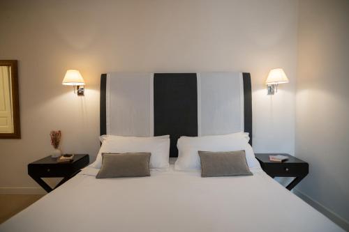 a bedroom with a large white bed with two night stands at Hotel Palazzo Cavalieri in Siracusa