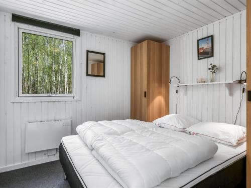 a large white bed in a room with a window at Holiday Home Tellervo - 1-5km from the sea by Interhome in Læsø