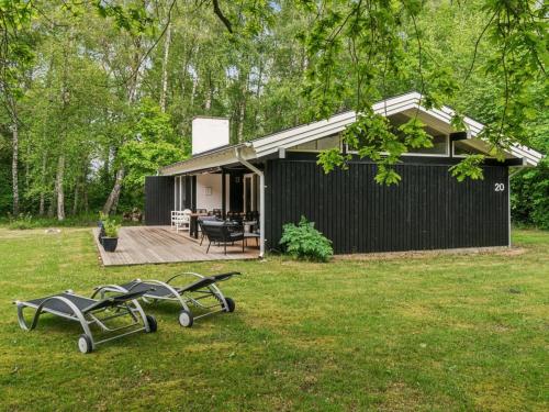 a black house with two picnic tables in the yard at Holiday Home Judyta - 250m to the inlet by Interhome in Nakke