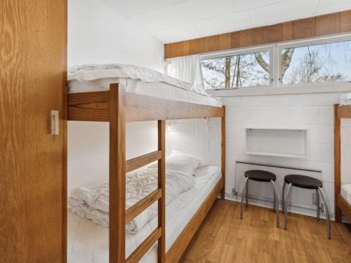 a bunk bed in a small room with two stools at Holiday Home Thara - 100m from the sea by Interhome in Sønderby