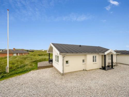 a white house with a black roof on a gravel driveway at Holiday Home Elfi - 700m from the sea by Interhome in Ringkøbing