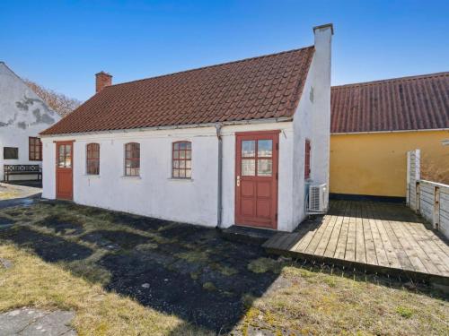 a white house with red doors in a yard at Holiday Home Bedri - 100m from the sea by Interhome in Læsø