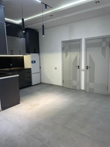 a large empty room with two doors and a kitchen at Квартира в центре города in Dushanbe