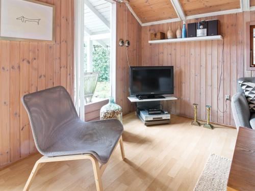 a living room with a chair and a television at Holiday Home Anttoni - 50km from the sea by Interhome in Ansager