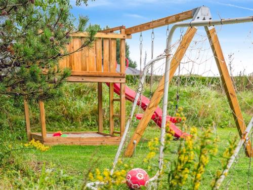 a playground with a swing in a yard at Holiday Home Thjodulf - 300m from the sea by Interhome in Knebel