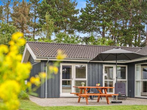 a picnic table with an umbrella in front of a shed at Holiday Home Thjodulf - 300m from the sea by Interhome in Knebel