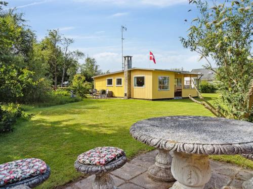 a stone table in a yard with a yellow house at Holiday Home Aslak - 600m from the sea by Interhome in Glesborg
