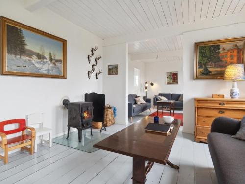 a living room with a table and a wood stove at Holiday Home Torbjörn - 2-5km from the sea by Interhome in Gudhjem