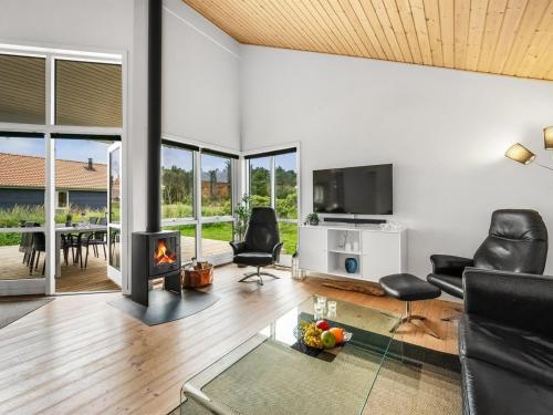 a living room with a fireplace and chairs and a television at Holiday Home Sylwia - from the sea by Interhome in Ulfborg