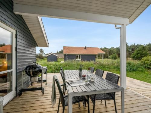 a patio with a table and chairs and a grill at Holiday Home Sylwia - from the sea by Interhome in Ulfborg