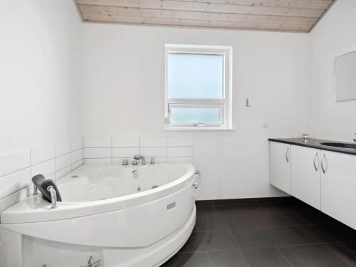 a white bathroom with a tub and a window at Holiday Home Pascal - 600m from the sea by Interhome in Augustenborg