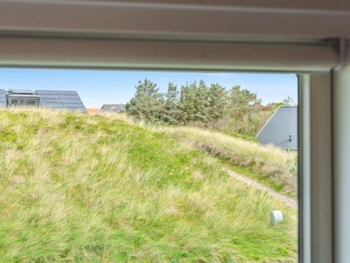 a view of a grassy hill through a window at Holiday Home Isabel - 500m from the sea by Interhome in Torsted