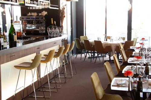 a restaurant with a bar with chairs and tables at Campanile NATURE - Clermont-Ferrand Nord Riom in Riom