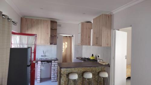 Una cocina con gabinetes de madera y un refrigerador negro. en Mooi Nooi, en Beaufort West