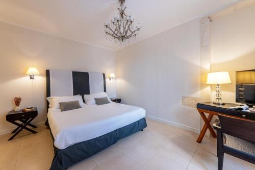 a bedroom with a white bed and a desk and a bed sidx sidx sidx sidx at Hotel Palazzo Cavalieri in Siracusa