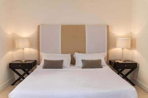a bedroom with a large white bed with two lamps at Hotel Palazzo Cavalieri in Siracusa