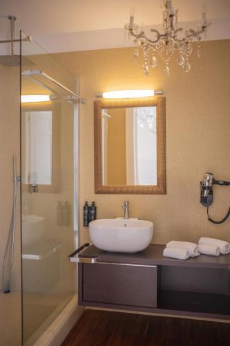 a bathroom with a sink and a mirror and a shower at Hotel Palazzo Cavalieri in Siracusa