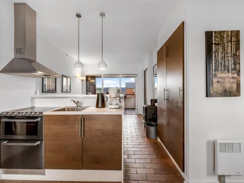 a kitchen with white walls and wooden cabinets at Apartment Alvy - 100m to the inlet by Interhome in Lemvig