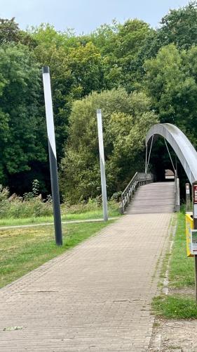 a bridge over a brick walkway with two metal poles at In De Wulf in Ypres