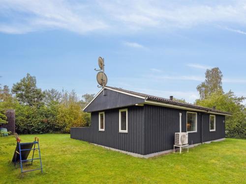 a black house on a grassy yard with at Holiday Home Sunaj by Interhome in Fårvang