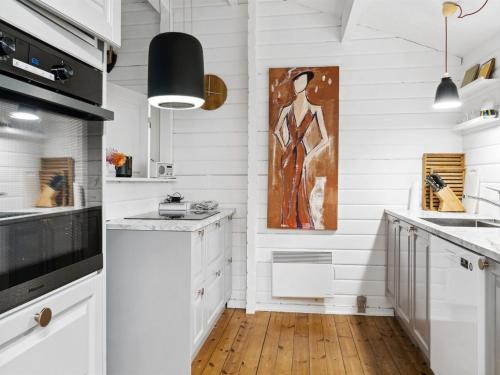 a kitchen with white cabinets and a painting on the wall at Holiday Home Neela - 300m from the sea by Interhome in Marielyst