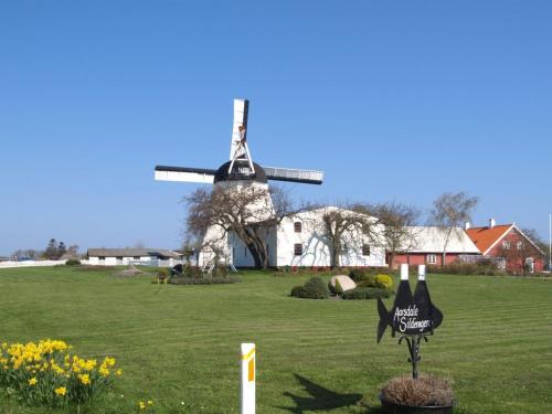 a windmill in a field with a sign in front at Holiday Home Elvira - 300m from the sea by Interhome in Svaneke