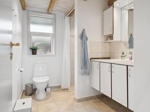 a white bathroom with a toilet and a window at Holiday Home Harald - 300m from the sea by Interhome in Ørsted