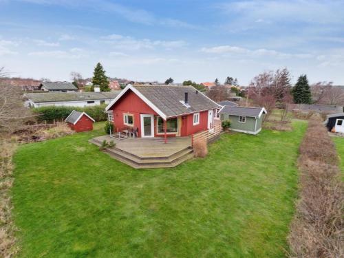 a red house on a green yard with a deck at Holiday Home Marlies - 300m from the sea by Interhome in Allinge
