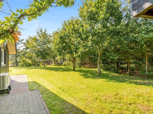 un patio abierto con árboles y una casa en Holiday Home Roska - 1-3km from the sea by Interhome, en Saltum