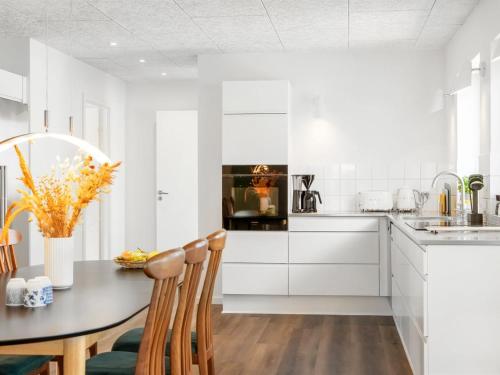 a kitchen with white cabinets and a table and chairs at Holiday Home Unge - 75m from the sea by Interhome in Torsted