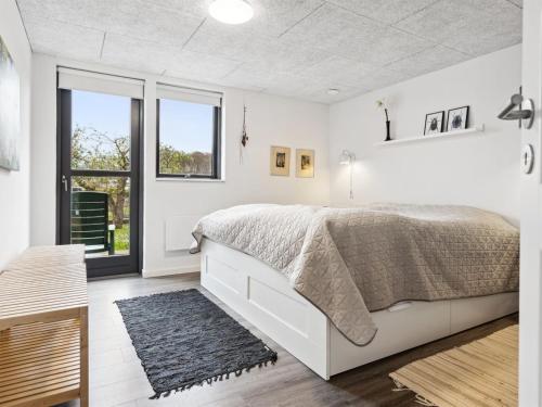 a white bedroom with a large bed and a window at Holiday Home Alona - 90m from the sea by Interhome in Allingåbro
