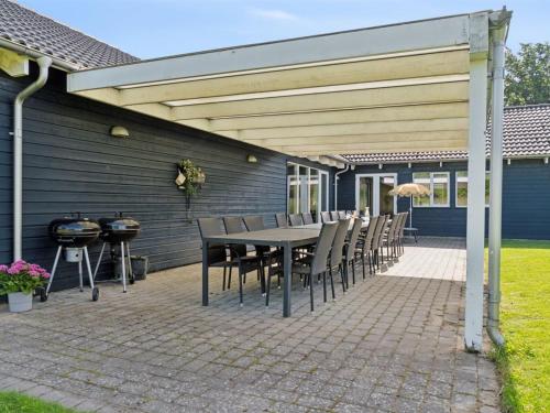a patio with a table and chairs and a grill at Holiday Home Jelke - 520m from the sea by Interhome in Tranekær