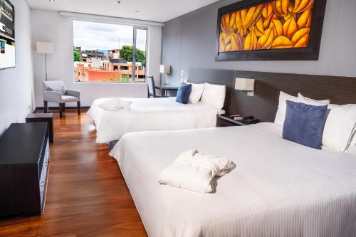 a hotel room with two beds and a window at One Sixteen Hotel in Bogotá