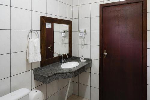 a bathroom with a sink and a mirror at Pousada Porto dos Casais in Praia do Rosa