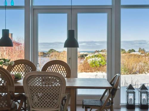 a dining room with a table and chairs and windows at Holiday Home Els - 1-8km from the sea by Interhome in Fårevejle