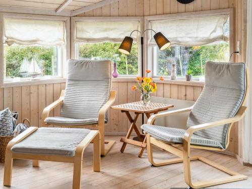 two chairs and a table in a room with windows at Holiday Home Thorke - 200m from the sea by Interhome in Nysted