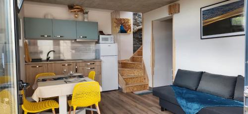 a small kitchen with a table and yellow chairs at Casas Floeca in Jardim do Mar