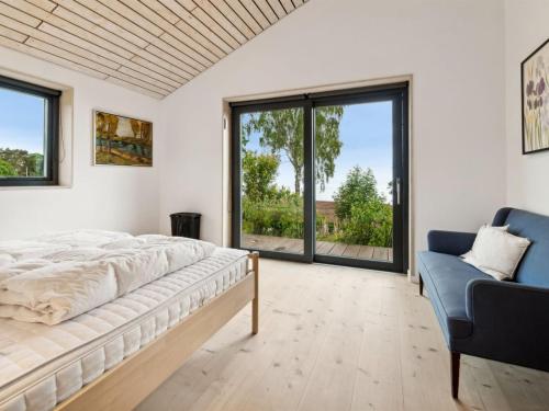 a bedroom with a bed and a couch and windows at Holiday Home Seetje - 200m from the sea by Interhome in Allinge